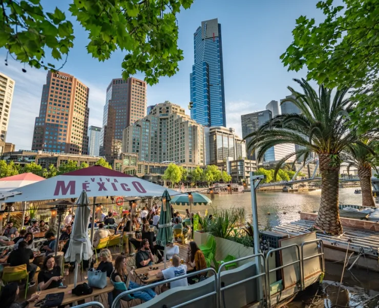 Large group of people enjoying good food and company on a moored restaurant on the Yarra River overlooking the city